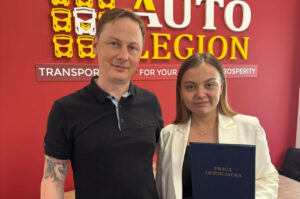 "the CEO and a student who wrote a thesis on the analysis of the financial system and economic stability of a transport and logistics company Autolegion stand at the company's brand board"